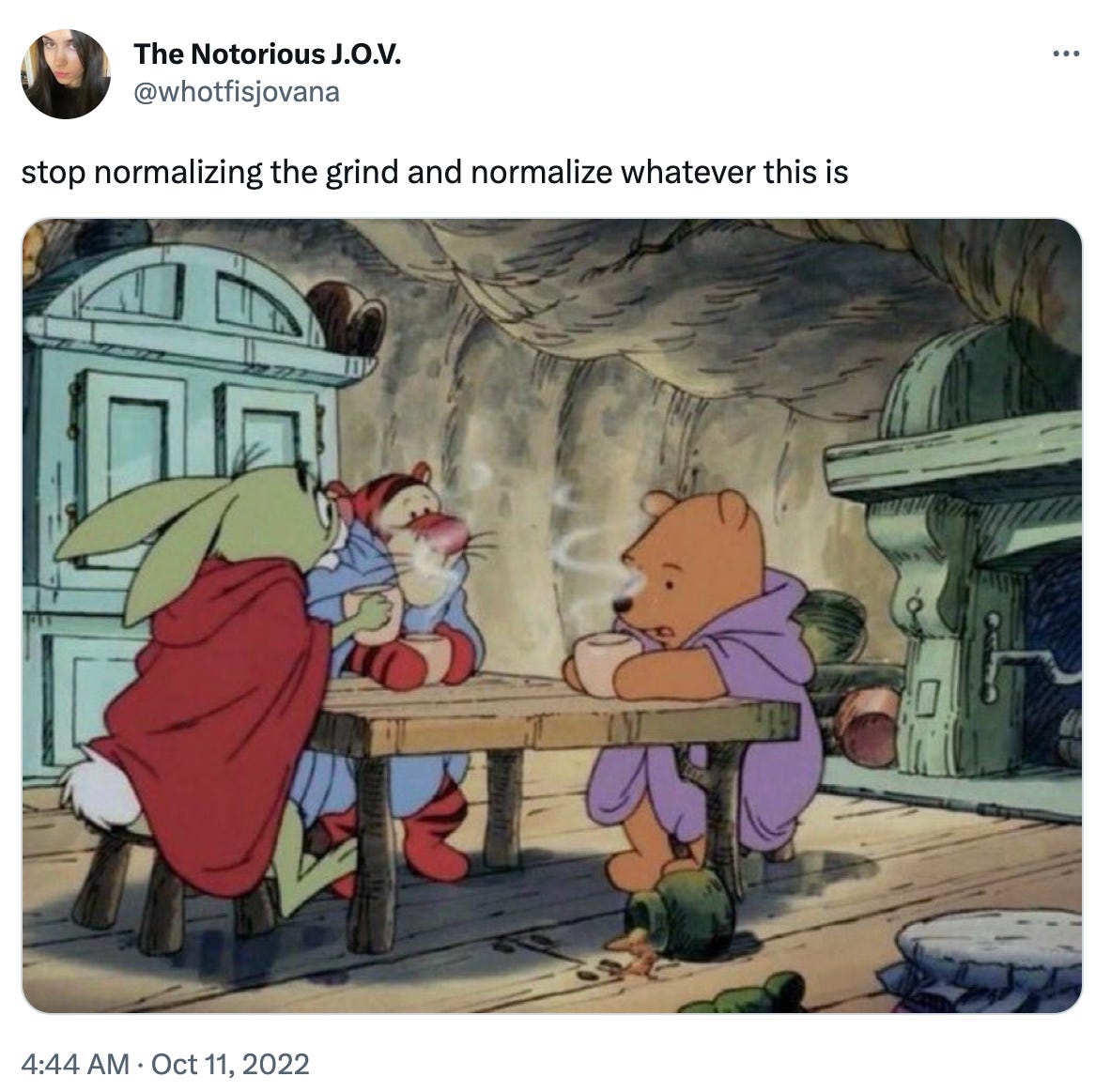 A tweet from @whotfisjovana. Text: stop normalizing the grind and normalize whatever this is. Underneath is a screenshot from the Disney Winnie the Pooh movies where Pooh, Rabbit and Tigger are wrapped up in blankets, sitting at a cozy wooden table with steaming mugs in their hands. 