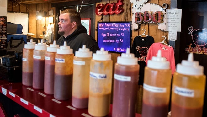 Allen Kuhn, a co-owner of 3 Hogs BBQ, waits on a customer behind a line of sauces, Monday, March 20, 2017. 3 Hogs BBQ, owned by Kuhn and Matt Albright, recently announced that their restaurant will expand to Spring Grove.