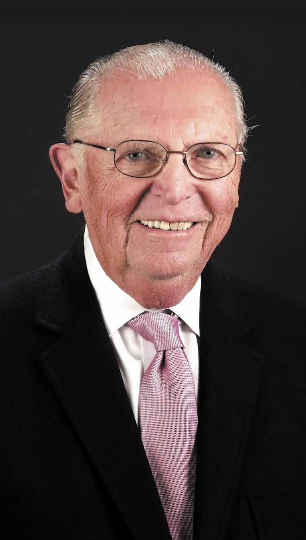 A smiling older man wearing suit and tie