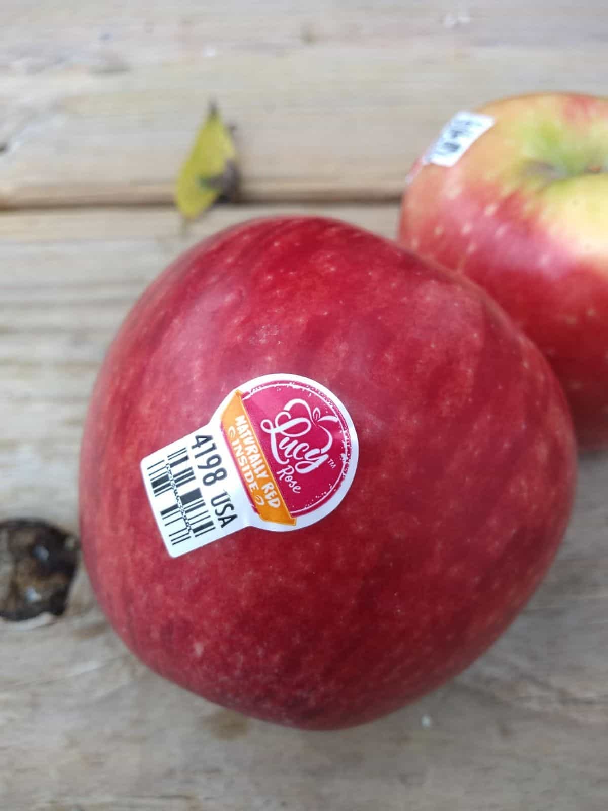 A Lucy Rose apple on a wood picnic table.