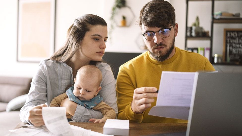 A couple and a baby look at their finances at home