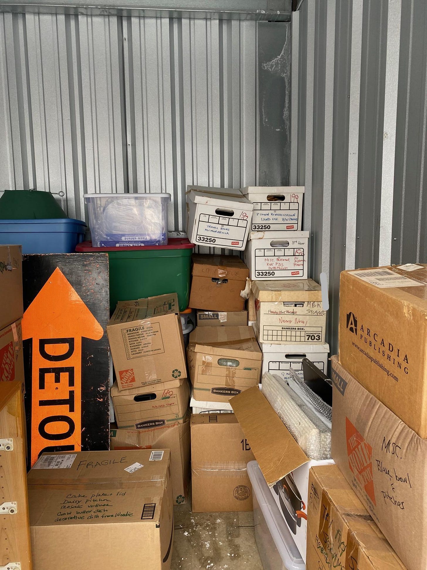 Image of boxes in a metal storage unit with visible black and orange detour sign and Christmas tree holder. Image of boxes in a metal storage unit with visible black and orange detour sign and Christmas tree holder.