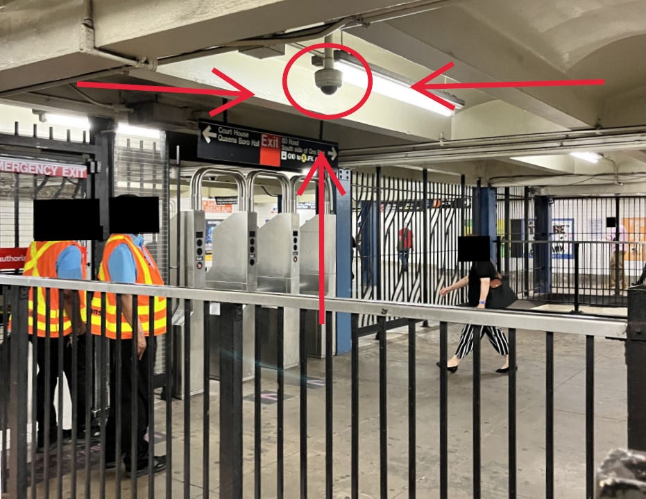 A picture of a subway entrance with a red circle and red arrows drawn on it pointing to a surveillance camera