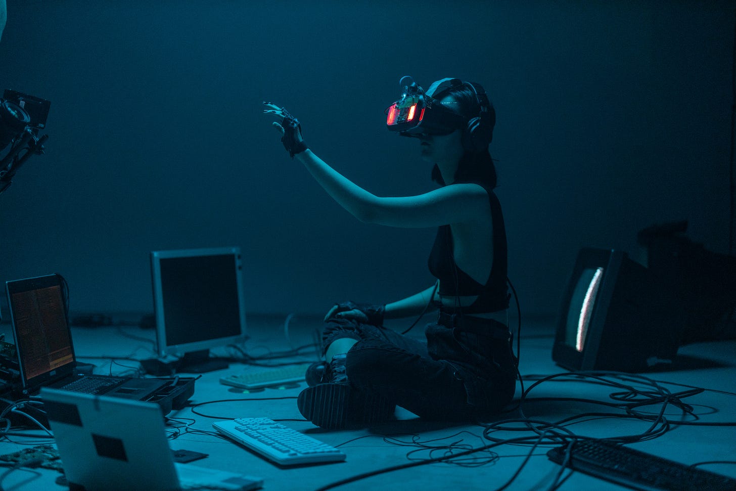 Girl in an alternate reality using a VR headset surrounded by computers in a dark room