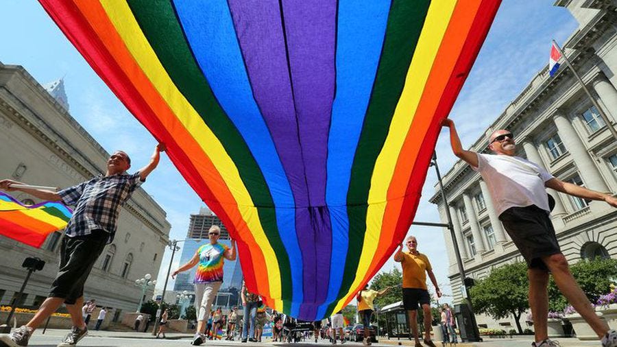 Paradegoers carry a huge rainbow flag past city hall on Lakeside Avenue during a Cleveland Pride Parade.