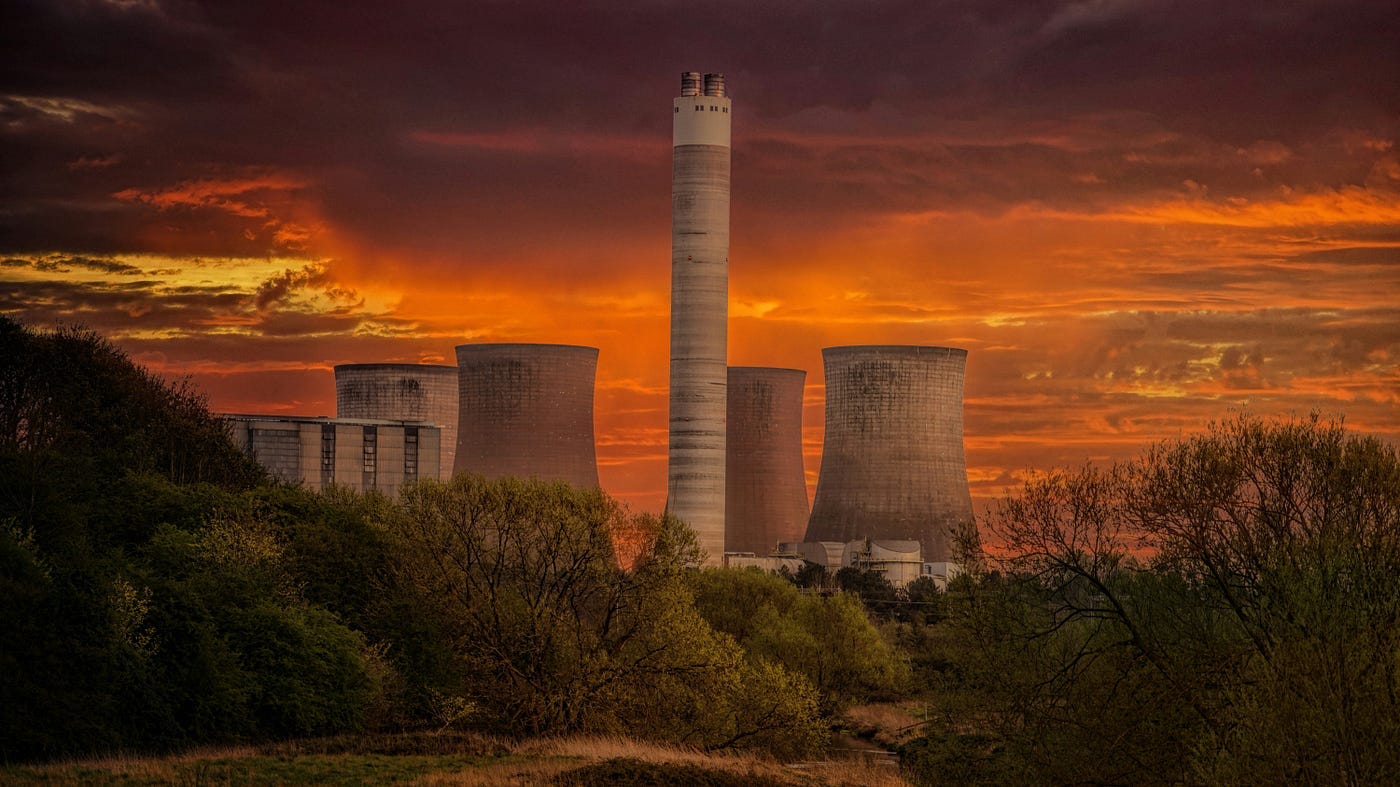 Smokestacks of a power plant against a hauntingly red background.