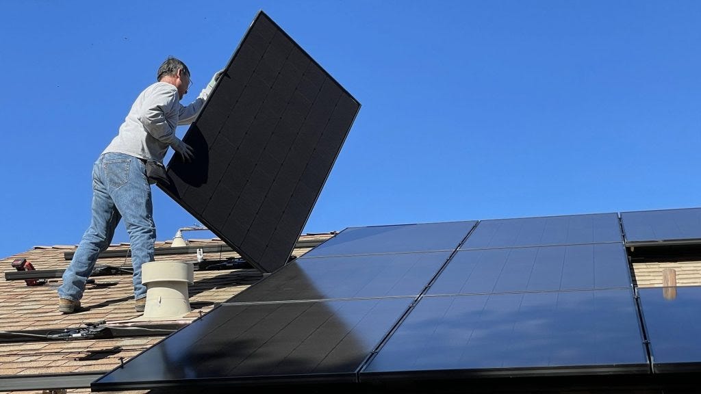 A photo of a man installing solar panels on a roof.