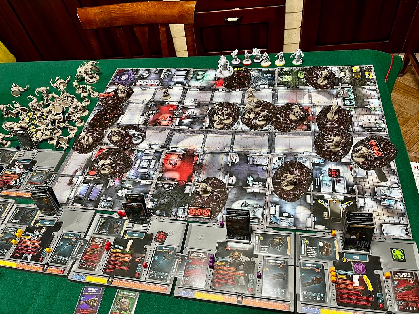 A table set with a winning game of Zombicide Invader: a board filled with plastic minims, cardboard tokens and cards. On top a group of survivors and a bot succesfully exiting the evacuation area of the map, scoring a victory against the Xeno