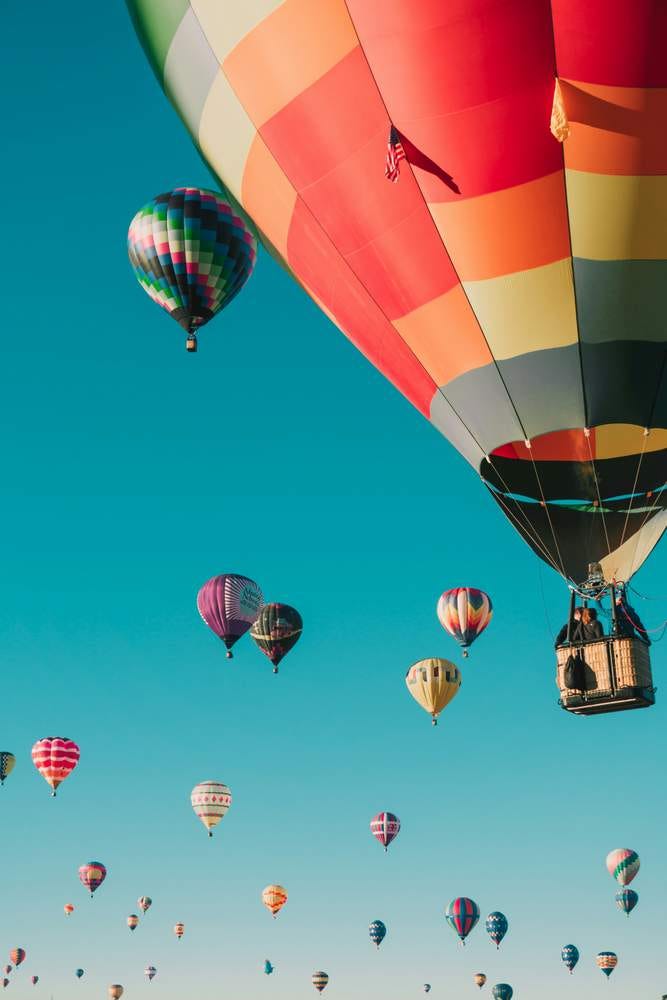 A sky full of colourful modern hot air balloons.