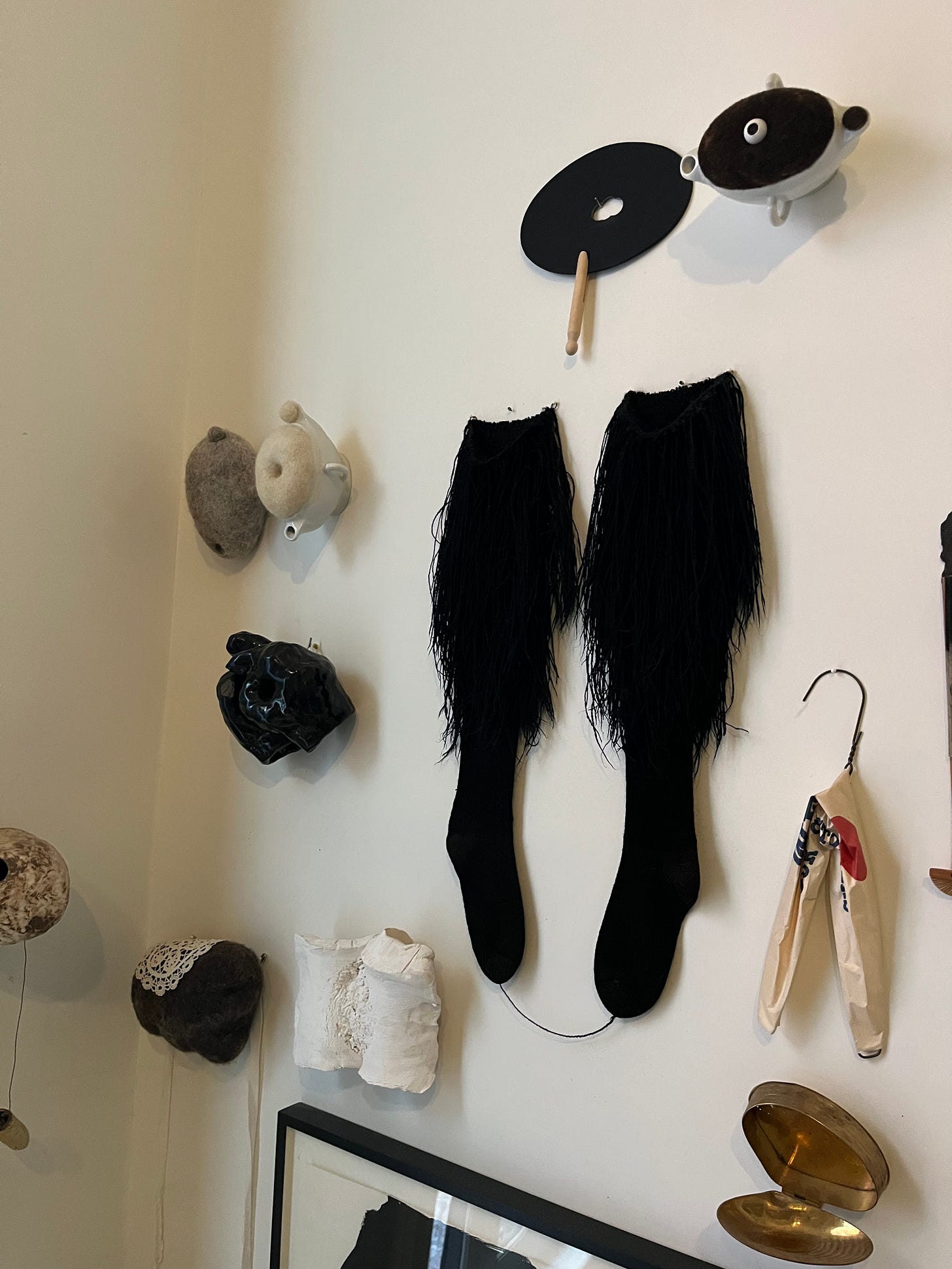 A wall display showing furry socks, teapots with felt lids, and other sculptural items.