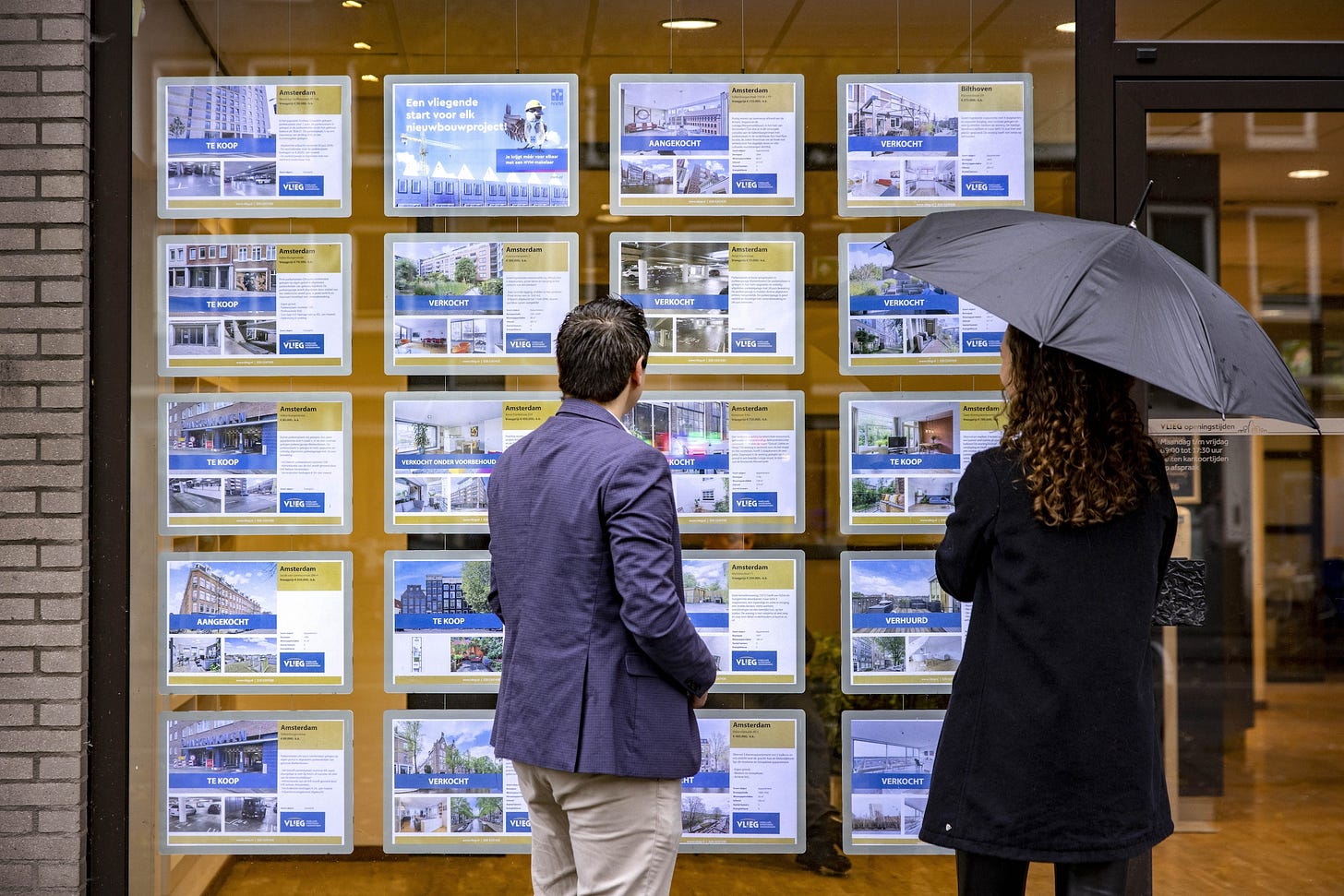 Woningaanbod in een etalage van een Amsterdams makelaarskantoor.