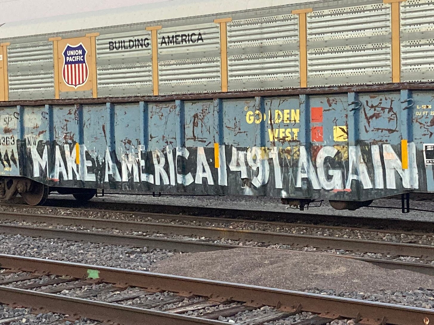 A heavily grafittied train: text painted on it reads: Make American 1491 again.