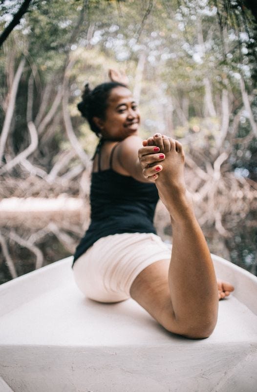 Person sitting and stretching, looking back over their shoulder at the camera with a big smile