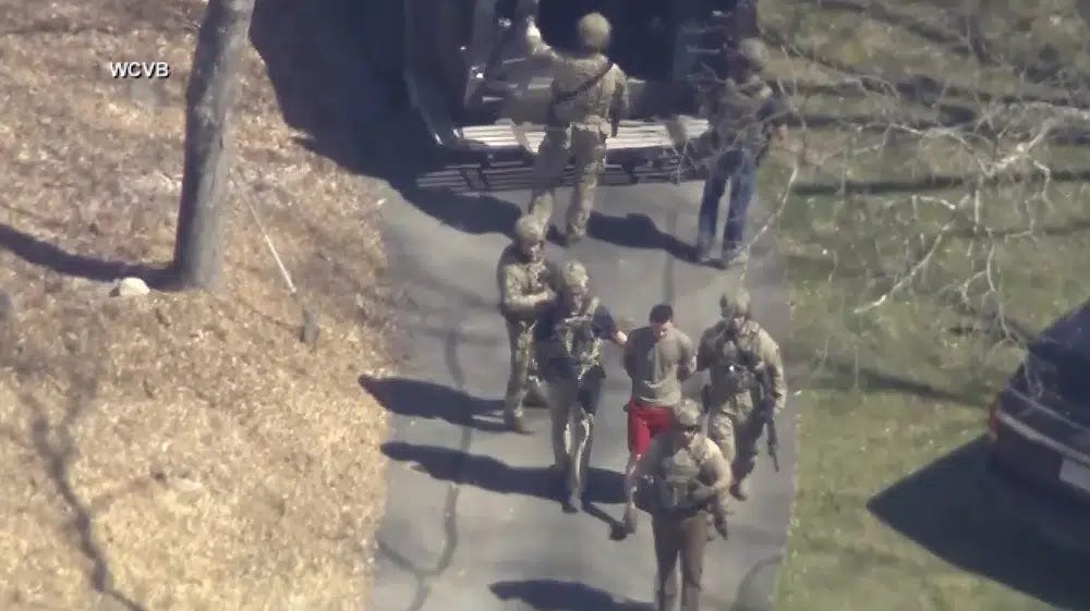 FILE - This image made from video provided by WCVB-TV, shows Jack Teixeira, in T-shirt and shorts, being taken into custody by armed tactical agents on Thursday, April 13, 2023, in Dighton, Mass. A judge is expected to hear arguments Thursday, April 27, over whether Teixeira, accused of leaking highly classified military documents about the Ukraine war and other issues, should remain in jail while he awaits trial. (WCVB-TV via AP, File)