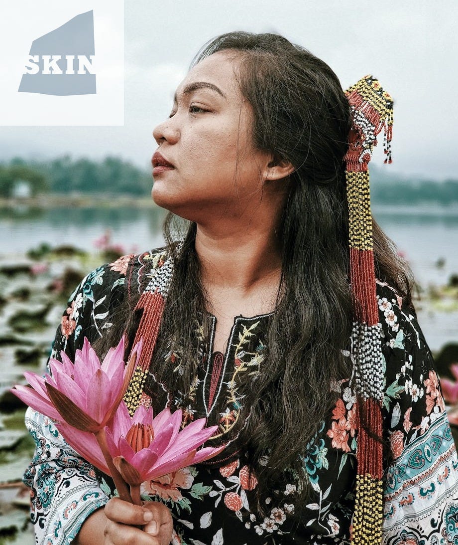 woman wearing black and multicolored floral long-sleeved blouse holding pink lotus flowers while facing her right right during daytime