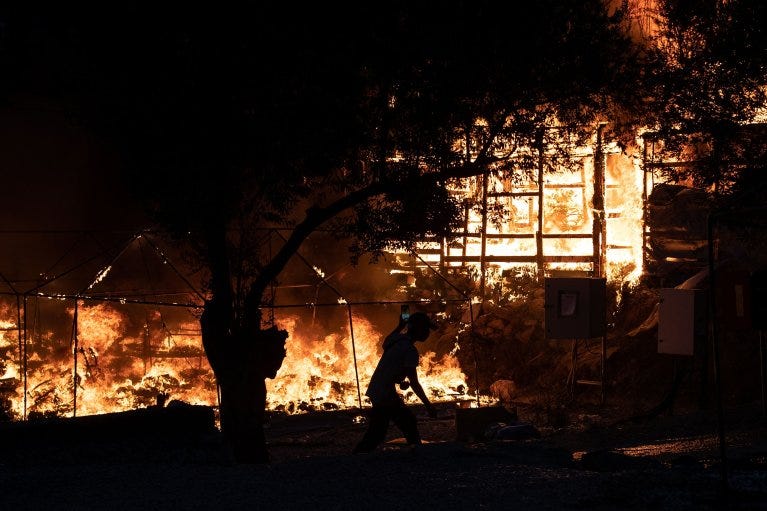 A man runs past burning shelters as a fire burns at the Moria camp on the island of Lesbos, Greece, September 9, 2020. REUTERS/Alkis Konstantinidis