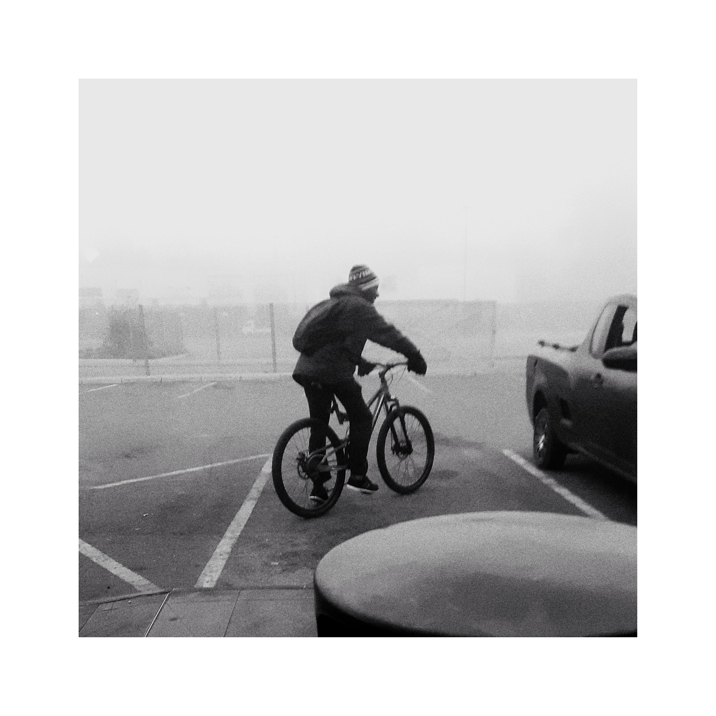 Man on a bicycle with a car to his right.