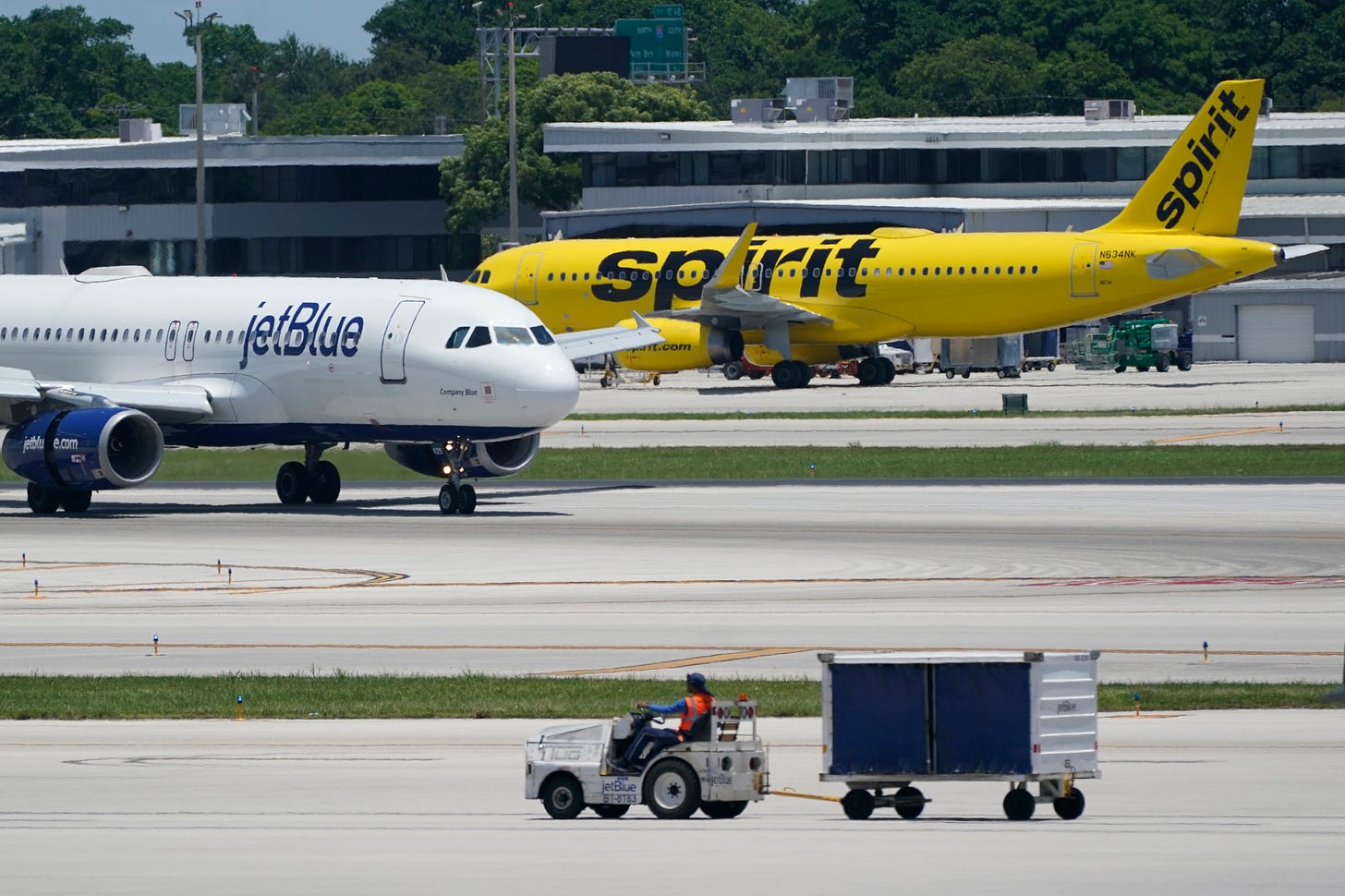 A JetBlue Airways Airbus A320, left, passes a Spirit Airlines Airbus A320 as it taxis on the runway.