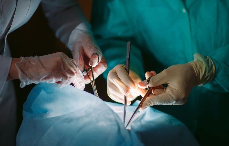 A close-up of surgeons hands holding medical instruments during a surgical operation.