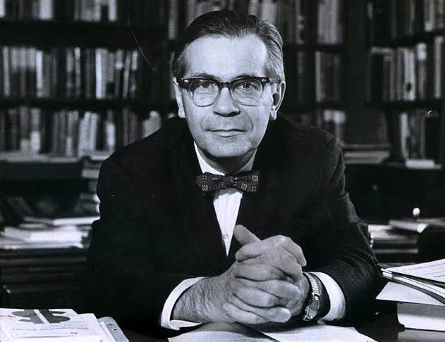 Black and white photo of historian Richard Hofstadter, wearing suit and glasses and looking directly at camera.