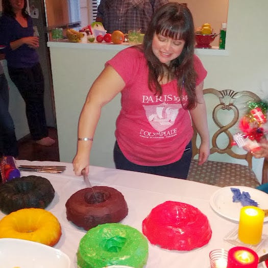 A woman cutting a round cake in the shape of the Olympic Rings