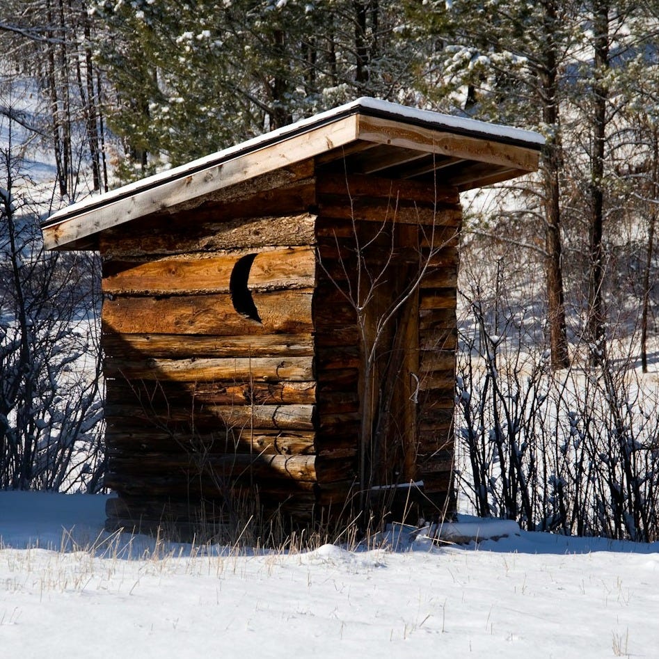 a small log cabin in the middle of a snowy field