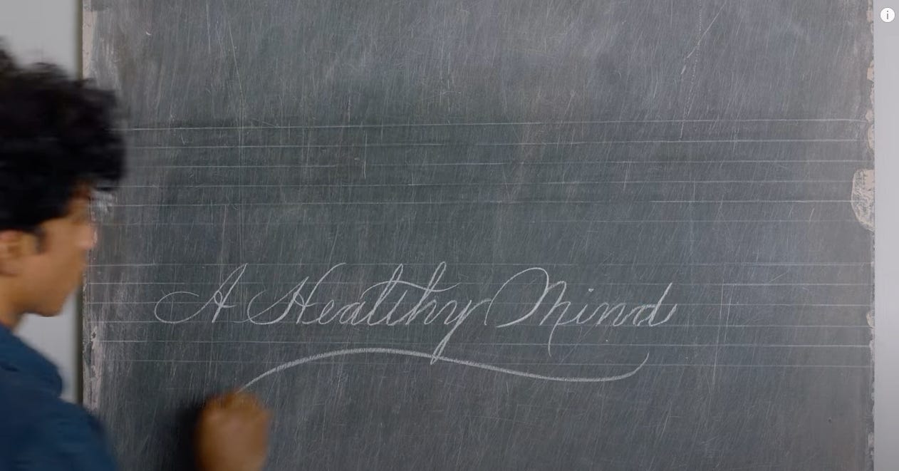 Rajiv writes on a chalkboard in cursive, "A Healthy Mind"