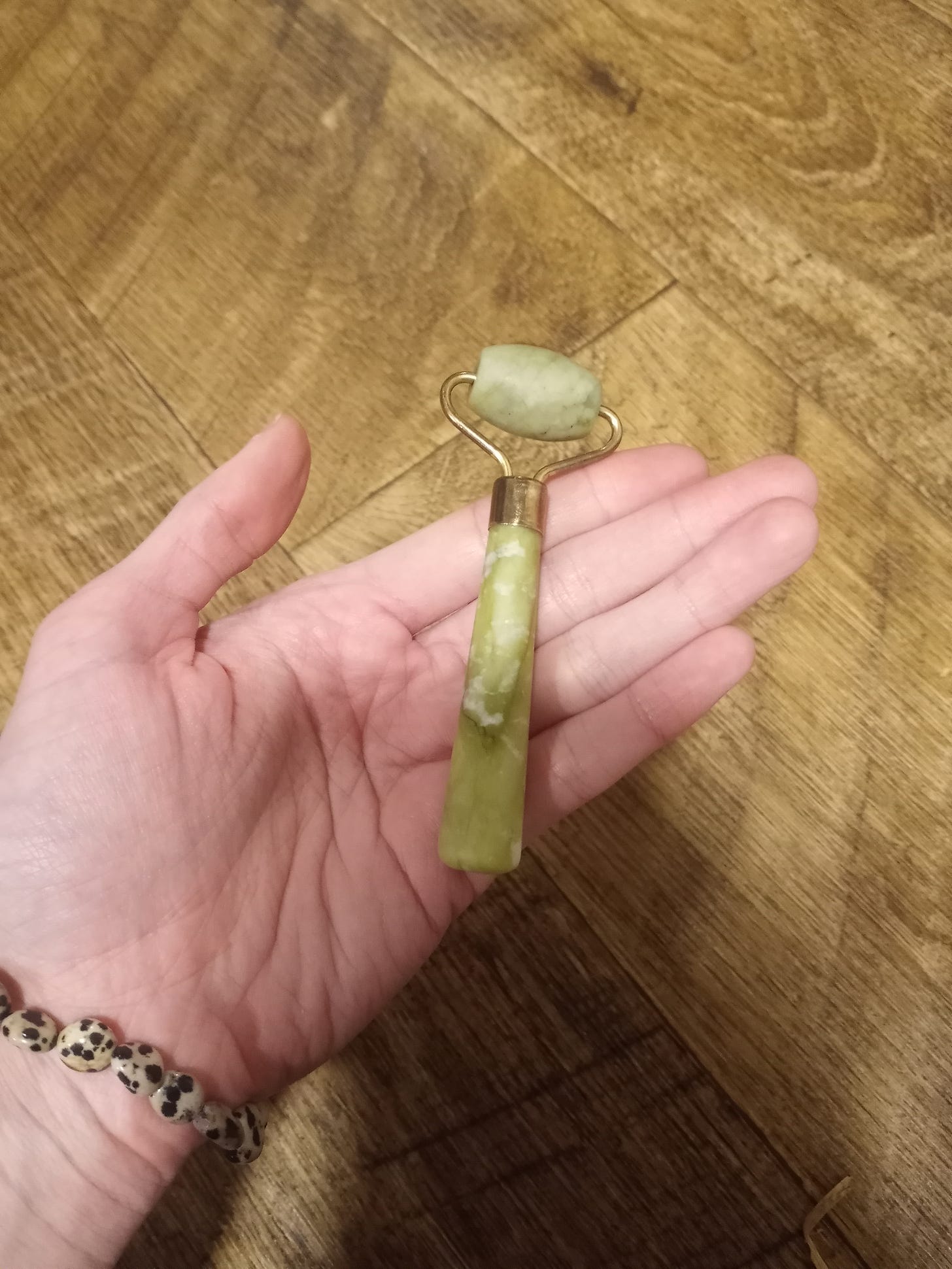 Picture of a green jade roller and a dalmatian jasper stone bracelet