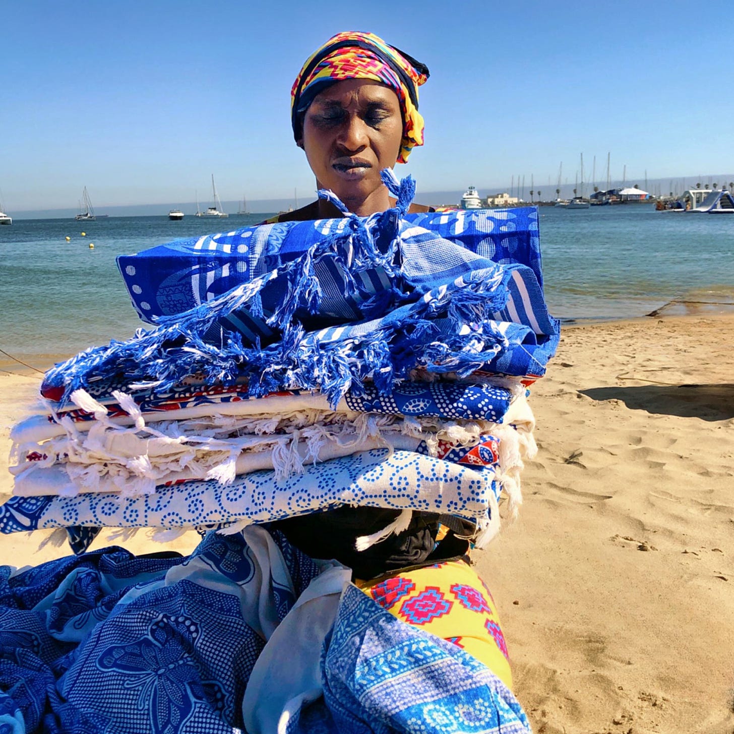 A beach vendor with a variety of blankets, creating a vibrant display.