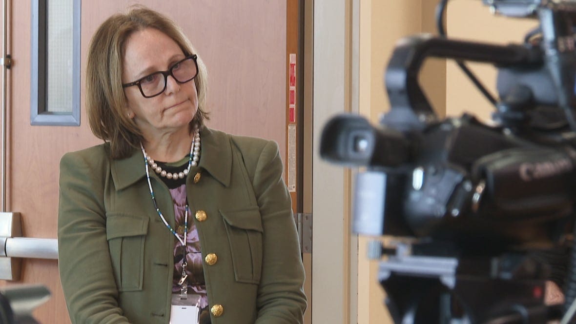 A woman stands in front of media cameras.