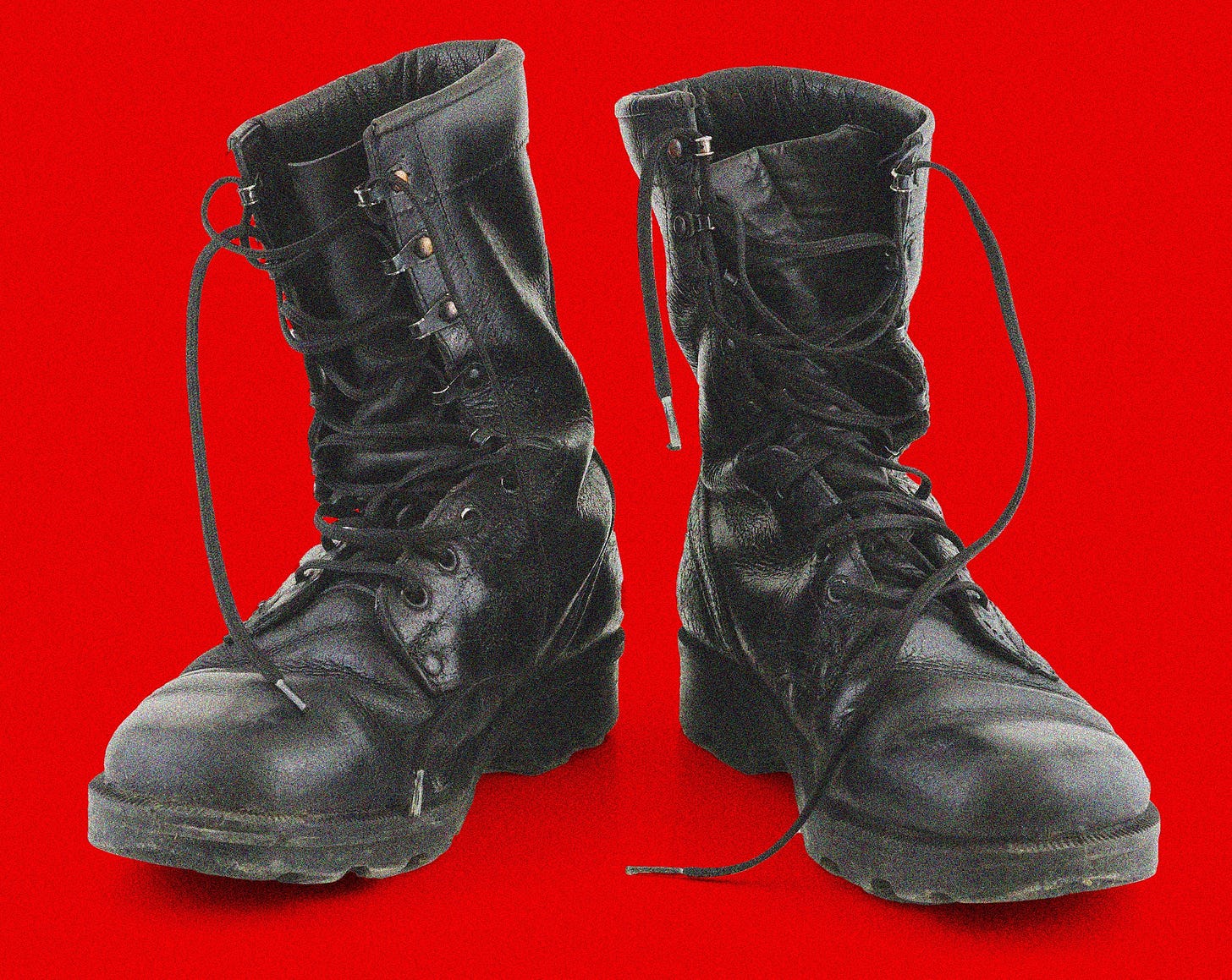 Black leather laceup boots on a red background