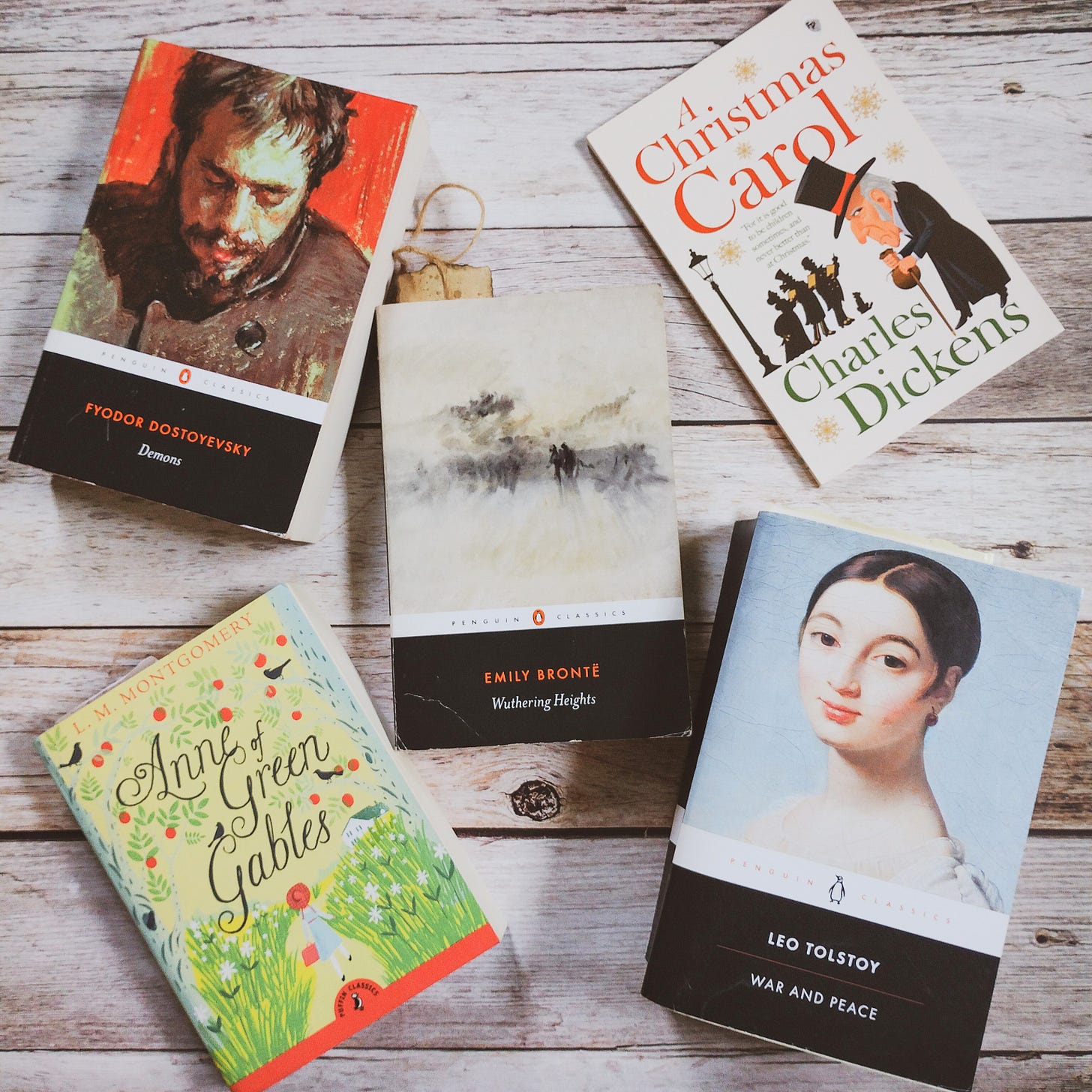 Books on a wooden table, War and Peace by Leo Tolstoy, Demons by Fyodor Dostoevsky, Wuthering Heights by Emily Brontë, Anne of Green Gables by L.M. Montgomery, A Christmas Carol by Charles Dickens