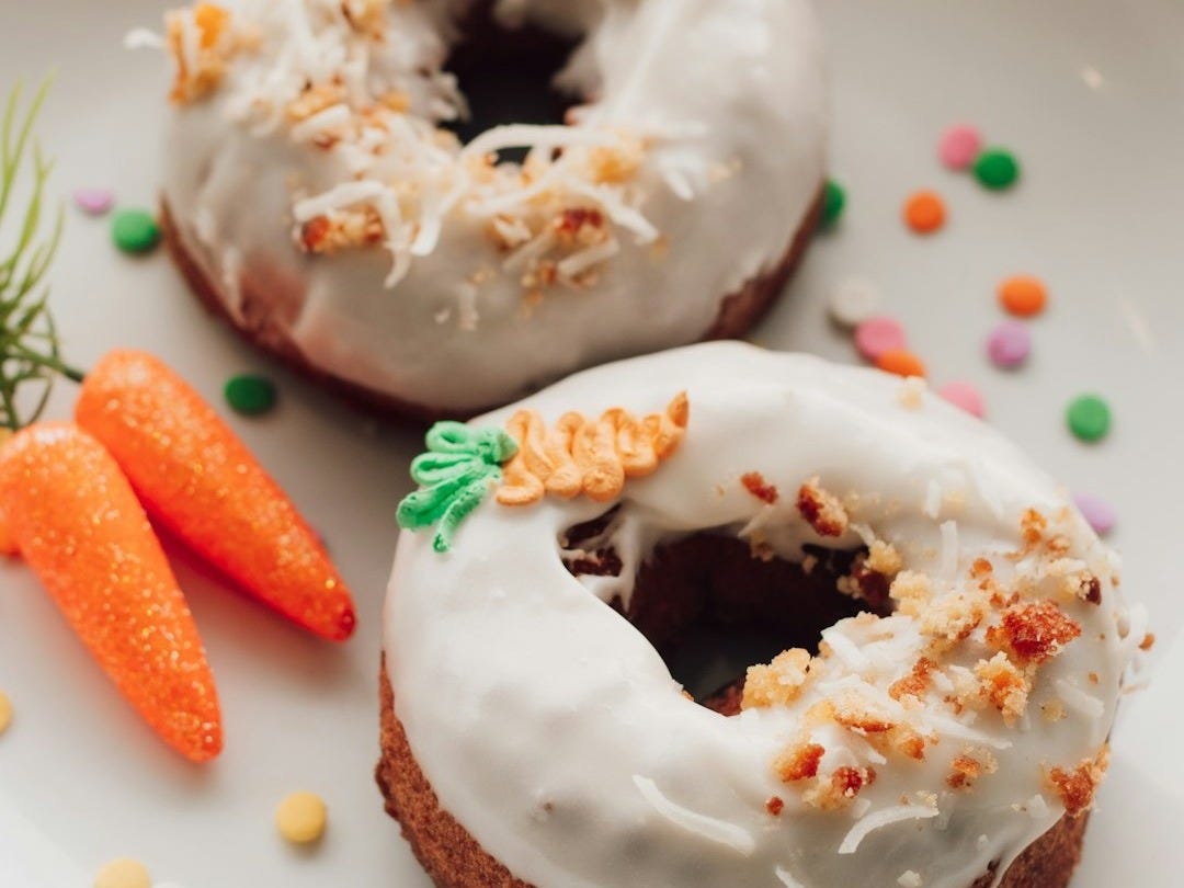 two glazed donuts with icing and sprinkles on a plate