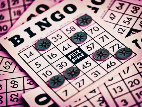 A single traditional bingo card atop a stack of bingo cards, with several markers in squares