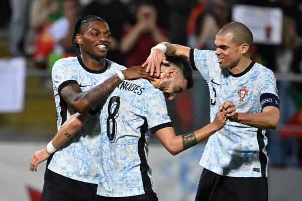 Portugal's midfielder Bruno Fernandes is congratulated for scoring his team's third goal by Portugal's forward Rafael Leao and Portugal's defender...