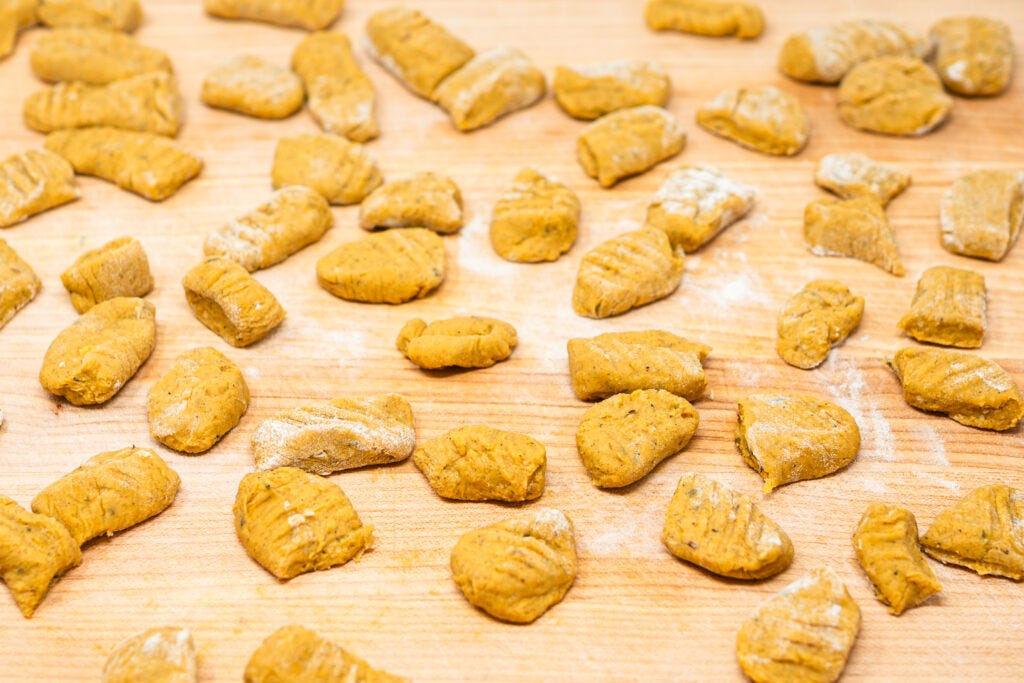 Handcrafted butternut squash gnocchi dusted with flour, arranged in rows on a wooden cutting board, showcasing the artisanal craftsmanship of homemade pasta. Handcrafted butternut squash gnocchi dusted with flour, arranged in rows on a wooden cutting board, showcasing the artisanal craftsmanship of homemade pasta.
