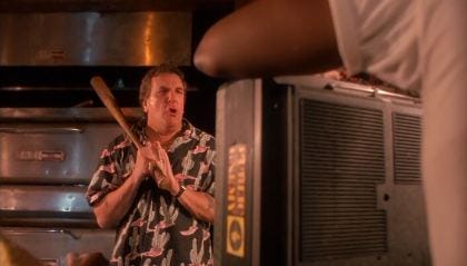 This image shows Sal Frangione (played by Danny Aiello) wielding a baseball bat in the final confrontation scene from Spike Lee's 1989 movie Do the Right Thing. Sal screams at the character Radio Raheem (played by Bill Nunn), whose back is the camera and who holds a "boom box."