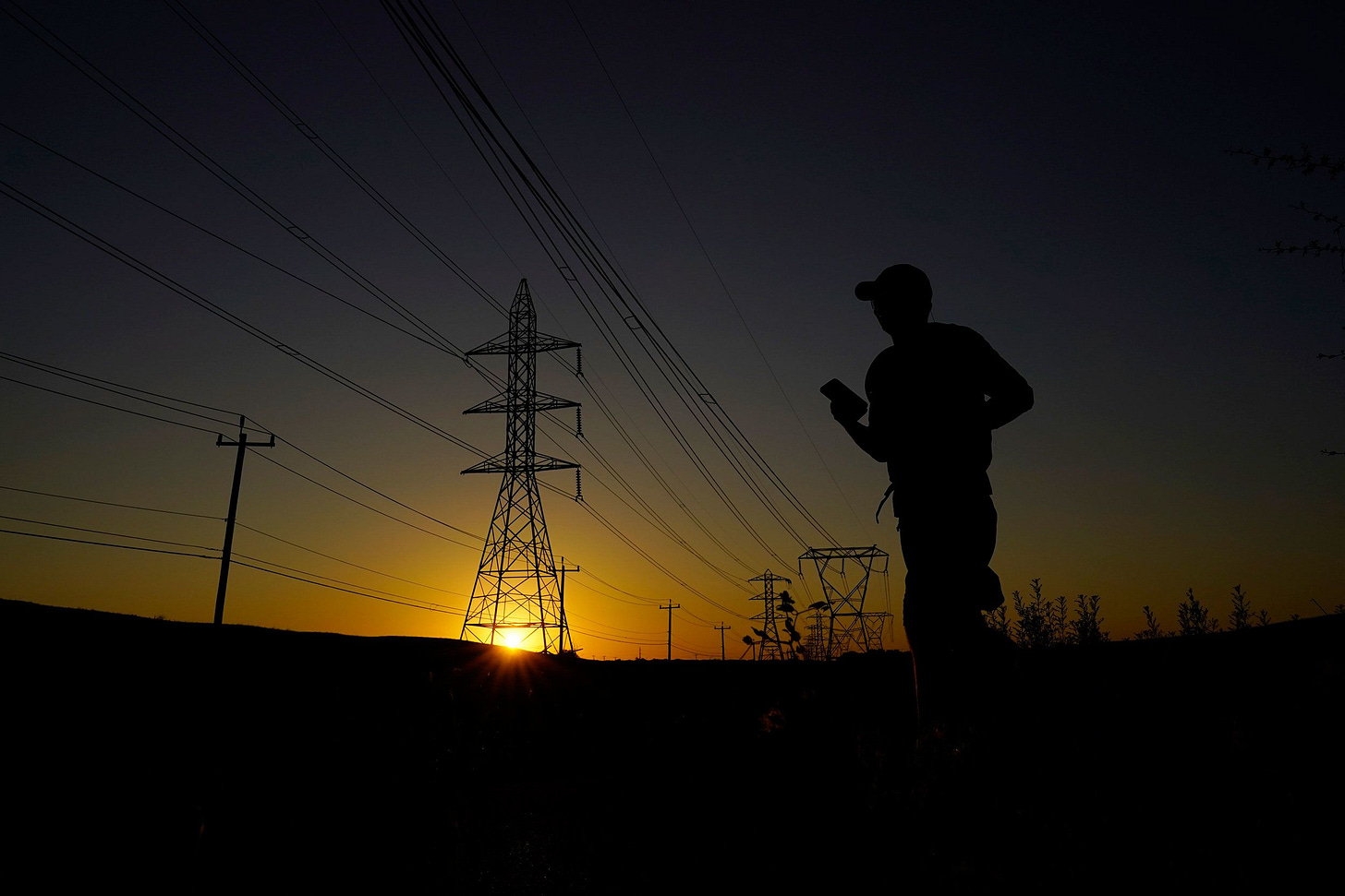 A jogger passes under power lines during an evening run on Monday in San Antonio. Nighttime temperatures will stay dangerously hot this week, forecasters have warned.