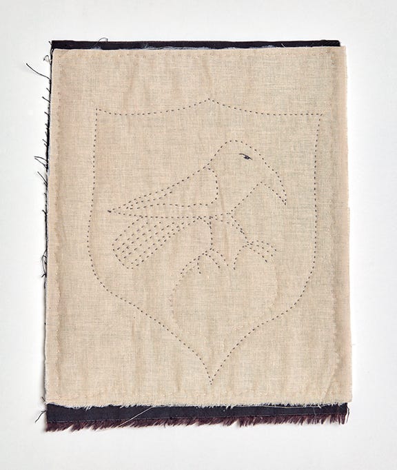 A stitched image of a bird sitting within a shield shape