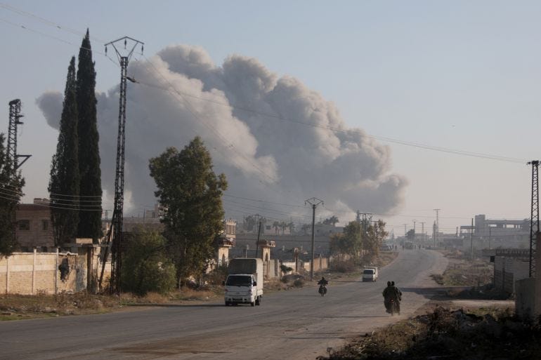 Fighters enter the Rashidin district on the outskirts of Aleppo on their motorbikes with smoke billowing in the background during fighting on November 29, 2024