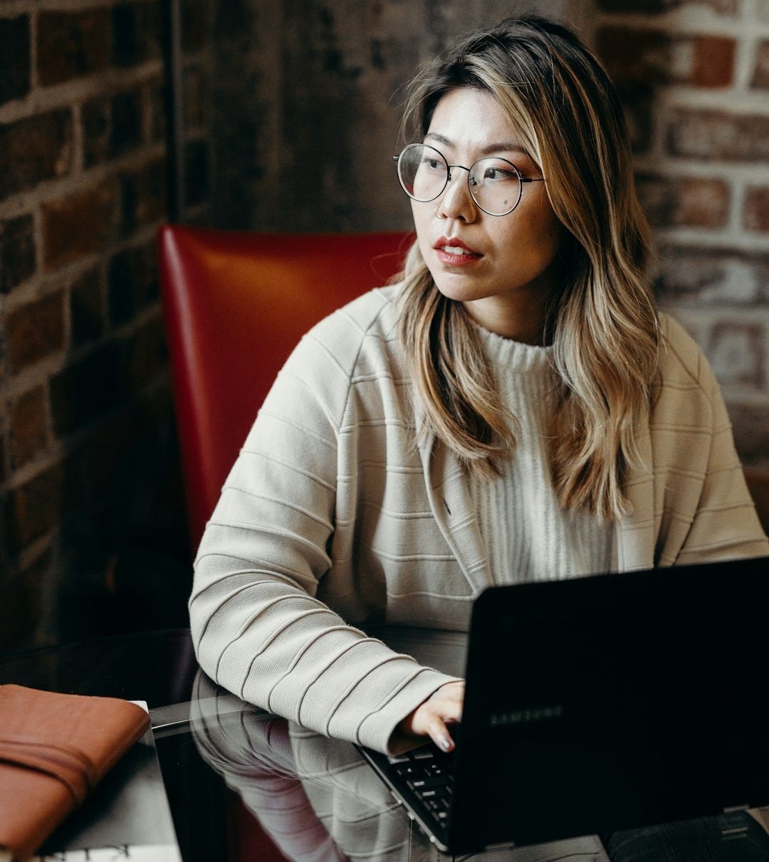 woman looking sideways while holding black laptop computer