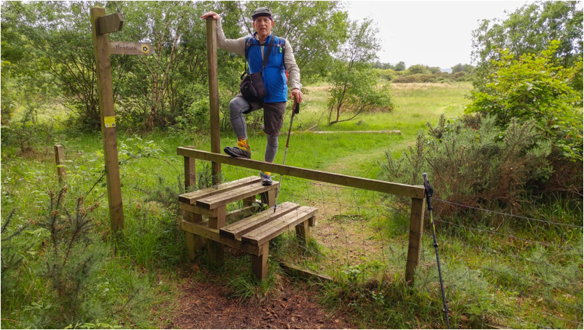 person using a stile to cross over a fence