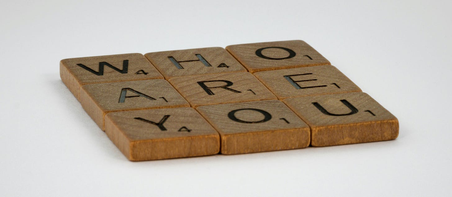 Holzplättchen mit Buchstaben, die den Satz "Who are you" ergeben. Auf weißem Grund.