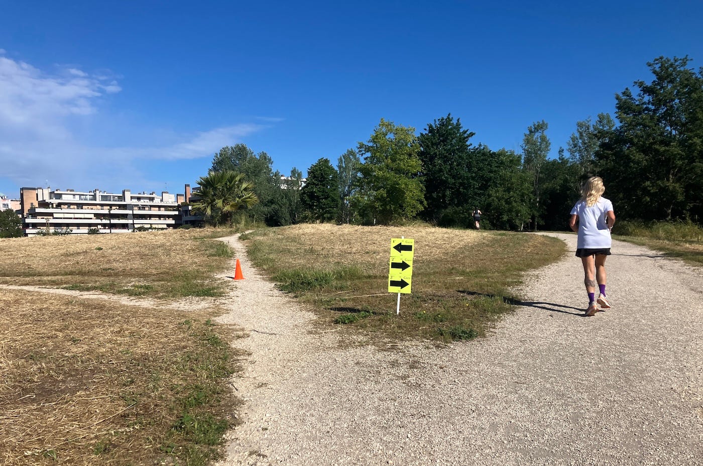 A runner on a wide path heading towards trees