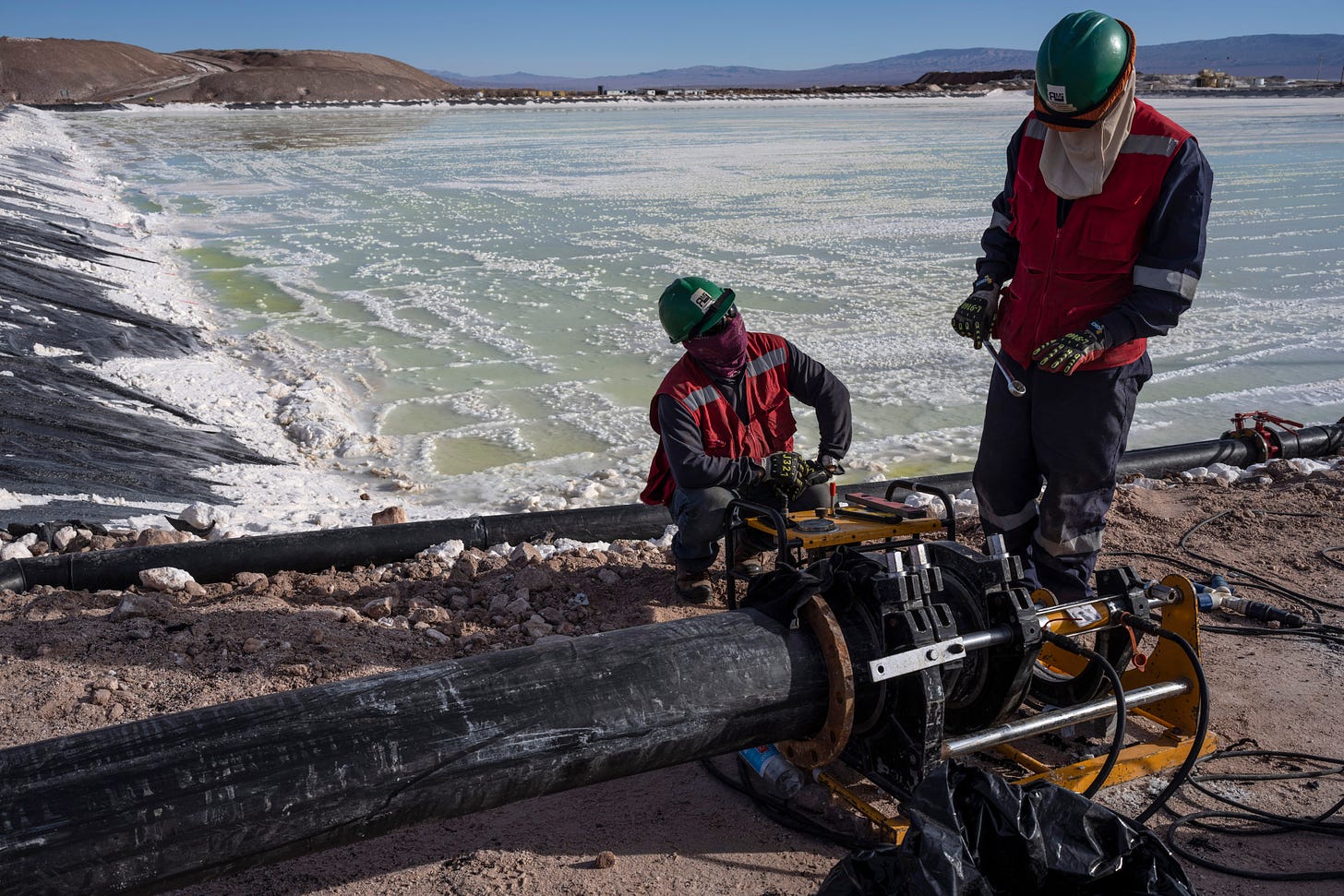 Workers perform maintenance at the pools where brine is evaporated at the lithium extraction plant facilities of the SQM Lithium company near Peine, Chile.