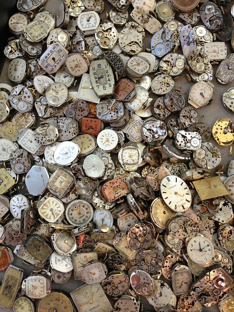 A large collection of watches and clocks on the sand.