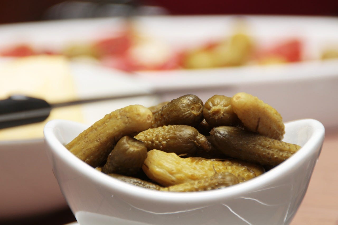 white bowl full of small pickled cucumbers