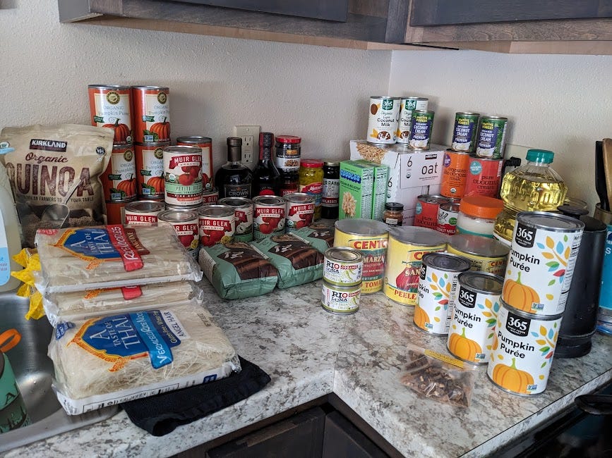 countertop full of canned goods, dried noodles, oil and quinoa