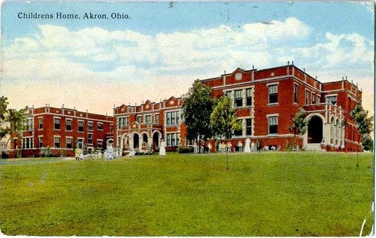 This may contain: an old photo of a school building in the middle of a field with people walking around it