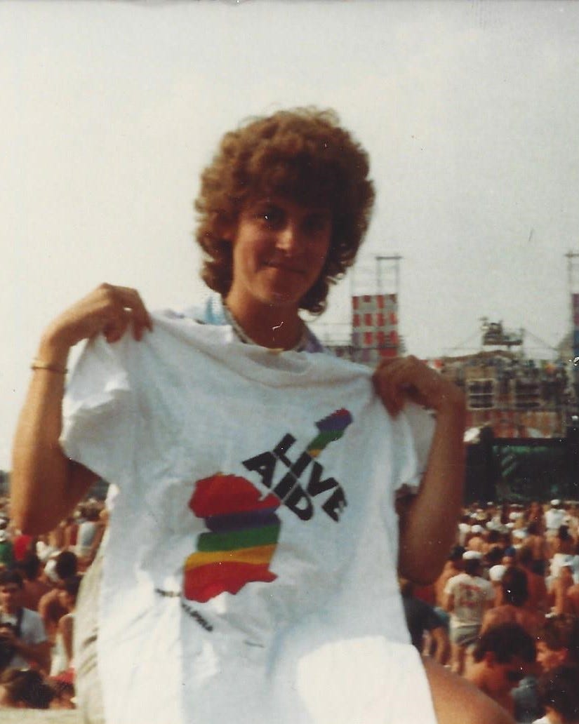 College-aged woman poses with souvenir t-shirt at Live Aid concert